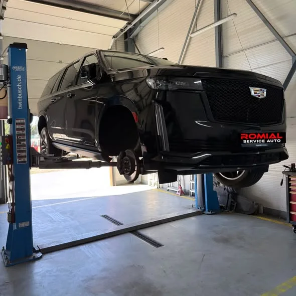 Cadillac Escalade negru ridicat pe elevator, cu roțile demontate